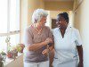 Smiling home caregiver and senior woman walking together