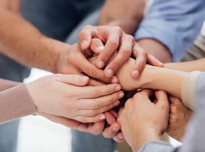 people stacking hands during group therapy session