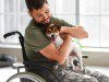 Young soldier in wheelchair with dog at home
