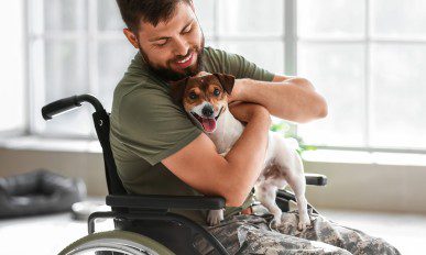 Young soldier in wheelchair with dog at home