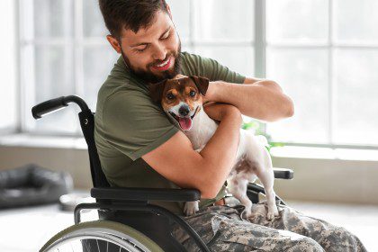 Young soldier in wheelchair with dog at home
