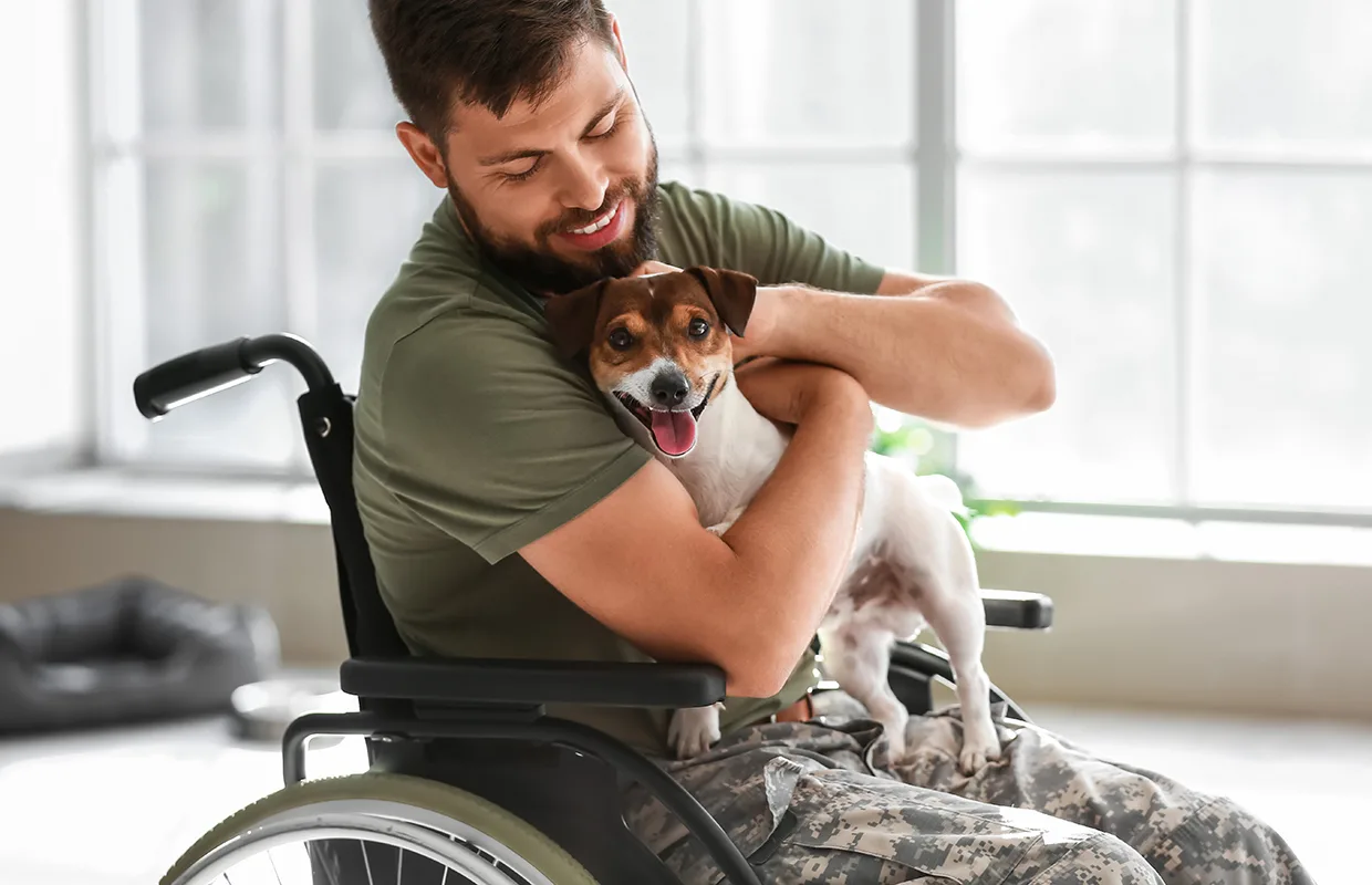 Young soldier in wheelchair with dog at home