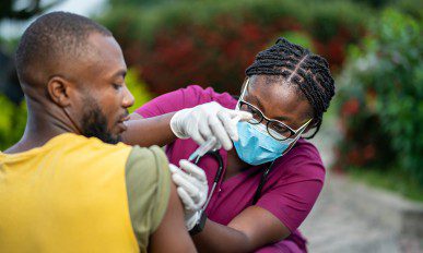image of young nurse in face mask, injecting young patient