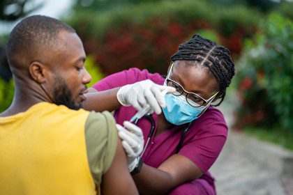 image of young nurse in face mask, injecting young patient